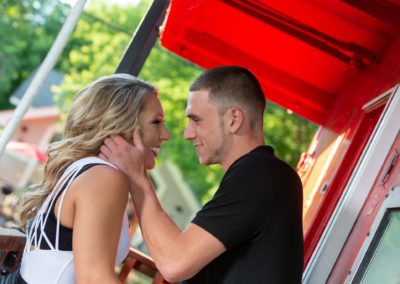 The couple posing for engagement photos on a caboose.