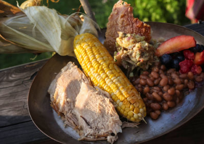 A food detail photograph with pork, corn, and beans.