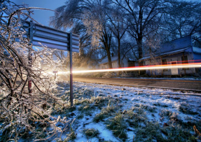 A photo at dusk of a passing car during an ice storm.