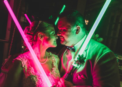 The bride and the groom with light sabers at the wedding reception.