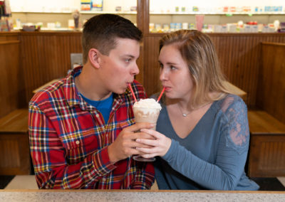 A young couple sharing a milkshake at the counter.