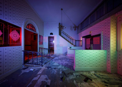 A photograph of the entrance lobby of an forsaken funeral home with red, blue, and green lights.