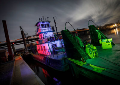 An image of a illuminated riverboat at night along the banks of a river.