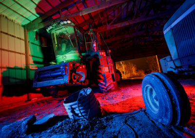 A picture of a John Deere combine at night with red, green, and blue hues.