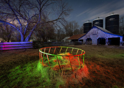 A photograph of a nocturnal farm scene with red, green, and blue lights.