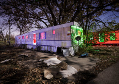 A nocturnal picture of two mobile homes illuminated with colored lights.