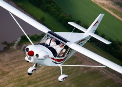 A photograph of a airplane flying over a farm fields.