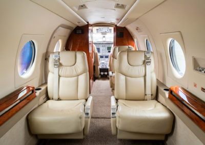 A cabin photo of a jet airplane with seats and windows.