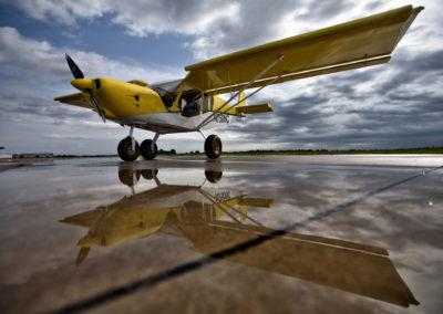 A photo of an airplane reflected in water on the tarmac.