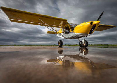 A photograph of an airplane reflected on a wet tarmac.