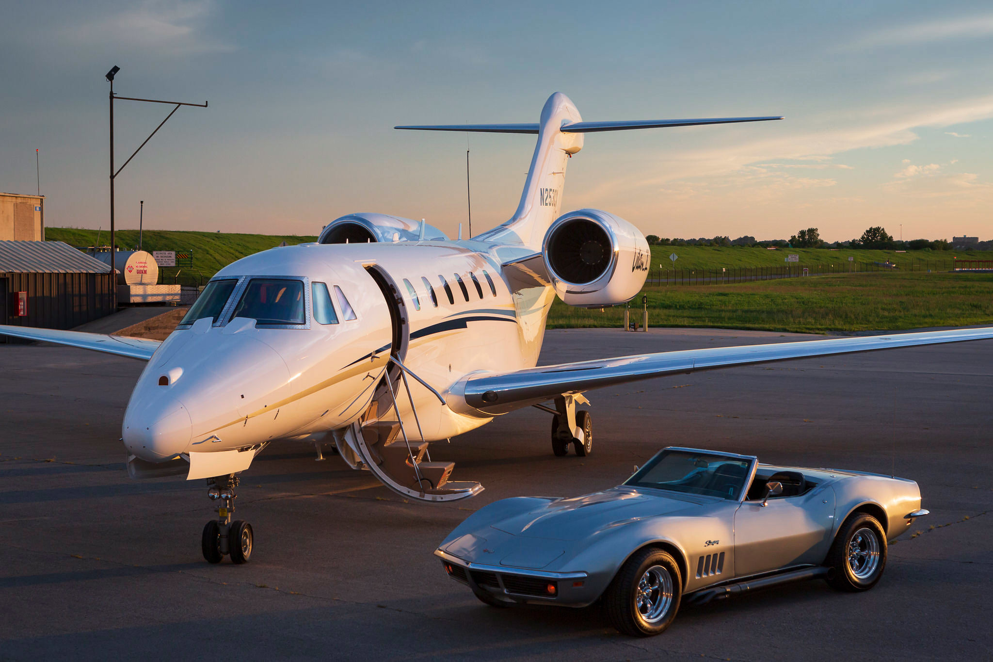 An image of a jet plane with a Corvette on the tarmac of an airport.