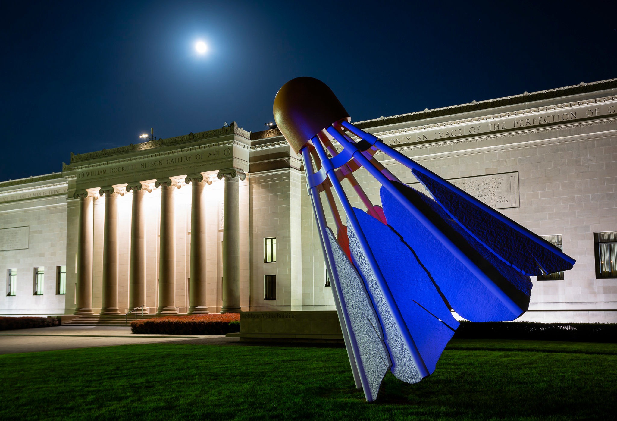 A nighttime photo of a sculpture in front of an art museum.